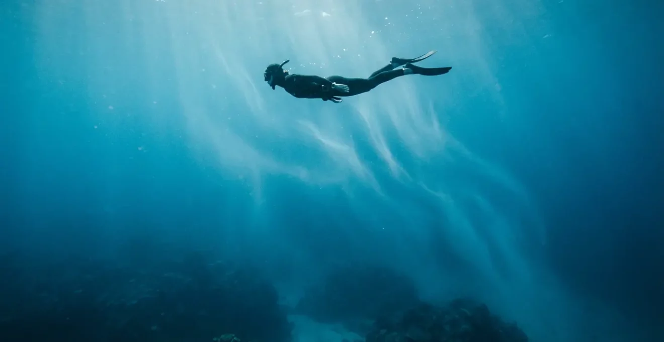 Plongeur en position horizontale glissant avec aisance dans un courant océanique, environnement sous-marin lumineux