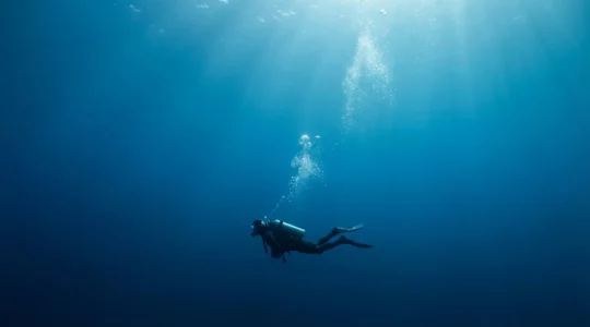Plongeur sous-marin en train d'effectuer un palier de décompression avec des bulles d'air s'échappant de son détendeur